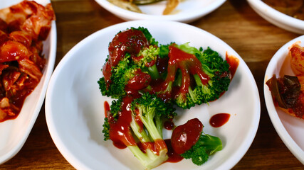 Fresh broccoli with savory brown sauce Korean side dish banchan served on white plate as part of...