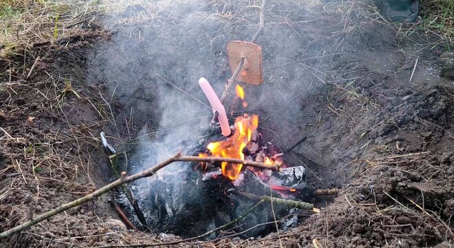 grilling a sausage at a campsite. A lifestyle of unity with nature. Bonfire in nature.