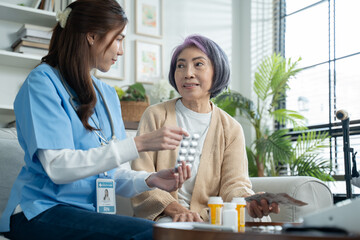 Nurse or caregiver assisting elderly woman with medication instructions during home visit or...