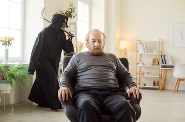 Serious sad lonely old senior man sitting in armchair in living room at home, with scary figure of...