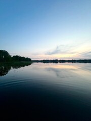Peaceful evening lake reflection, sky and trees silhouettes on the lake surface, summer lake in the...