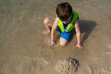 Summer vacation. Small child Playing With Sand Sitting On Sea Shore. 