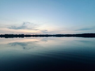 Peaceful evening lake reflection, sky and trees silhouettes on the lake surface, summer lake in the...