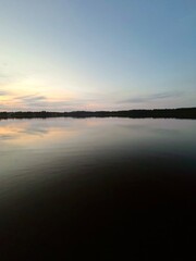 Peaceful evening lake reflection, sky and trees silhouettes on the lake surface, summer lake in the...