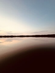 Peaceful evening lake reflection, sky and trees silhouettes on the lake surface, summer lake in the...