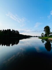 Peaceful evening lake reflection, sky and trees silhouettes on the lake surface, summer lake in the...