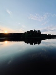 Peaceful evening lake reflection, sky and trees silhouettes on the lake surface, summer lake in the...