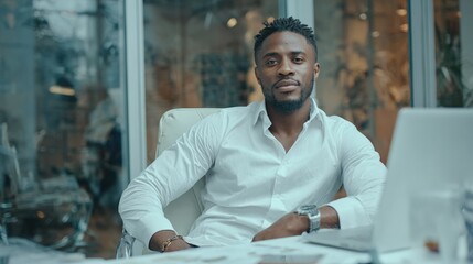 Confident African American businessman sitting in stylish office, laptop screen empty, room for message.