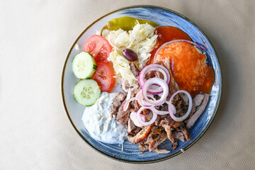Greek food, gyros with onions, coleslaw, rice with sauce and tzatziki on a plate in a restaurant,...