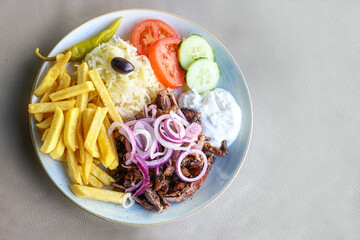 Gyros with a lot of onions, French fries, coleslaw, salad and tzatziki on a plate in a restaurant,...
