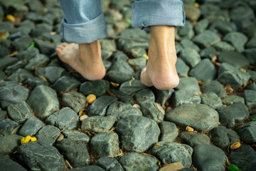 Close-up of barefoot woman walking on gravel ground in a peaceful forest retreat during early morning light. Self-care, emotional healing, and connection with nature for mental balance. Mindfulness.