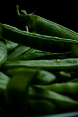 Juicy green peas close up in dark dramatic lighting macro texture