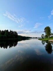 Peaceful evening lake reflection, sky and trees silhouettes on the lake surface, summer lake in the...