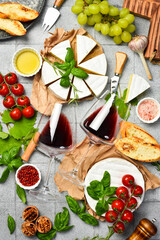 Composition of wine, Brie cheese, toasted bread, oil, grapes and nuts. Vertical photo. On a stone...