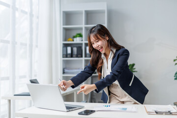 Young asian manager pointing at laptop screen celebrating successful project, business achievement...