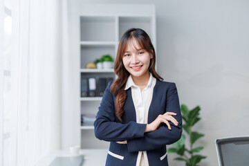 Portrait of a young asian businesswoman standing with arms crossed and smiling in a modern office