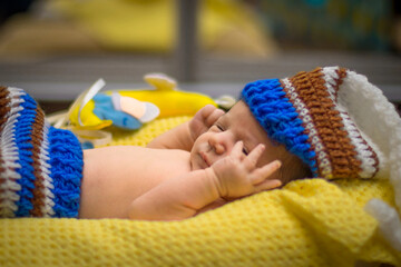 sleeping newborn dressed as a gnome baby on a yellow blanket