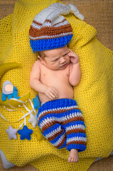 sleeping newborn dressed as a gnome baby on a yellow blanket