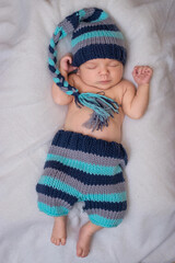 sleeping newborn dressed as a gnome baby on a white blanket