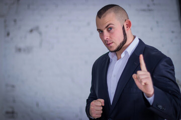 Strong man, bodyguard in a suit against the backdrop of the wall