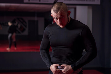 Beefy man in a black t-shirt in the gym with mirror