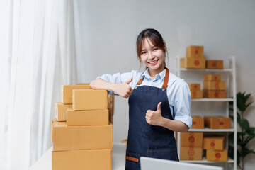 Young entrepreneur woman showing thumbs up, satisfied with her sales in her office or warehouse