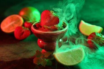 Hookah bowl with limes, strawberries, mint and smoke on black table, closeup