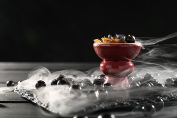 Hookah bowl with currants and smoke on black table, closeup. Space for text