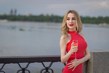 A girl stands by the river with a champagne tank