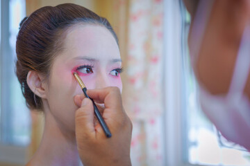 Beautiful Asian female tourist receives traditional Geisha or Maiko makeup, an ancient Japanese culture for beauty by professional make-up artist.