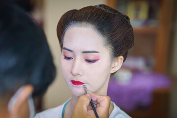 Beautiful Asian female tourist receives traditional Geisha or Maiko makeup, an ancient Japanese...