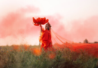 Beautiful girl in a red dress in a poppy field with a big poppy