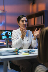 Asian project manager discussing project strategy with colleague during late night meeting in office