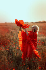 Beautiful girl in a red dress in a poppy field with a big poppy