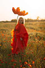 Beautiful girl in a red dress in a poppy field with a big poppy