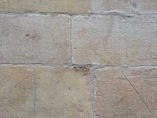 Close-up of weathered stone wall with visible scratches, texture