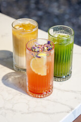 Assorted summer lemonades in glass jars with fresh fruits, ice, and garnishes