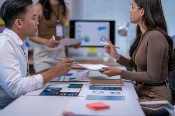 group of people are sitting at a table with papers and graphs in front of them