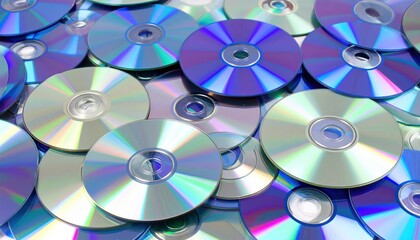 A close up view of numerous CDs and DVDs piled together showcasing their iridescent surfaces and reflective properties