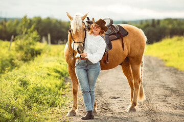 A woman, proudly wearing a cowboy hat, stands next to her horse