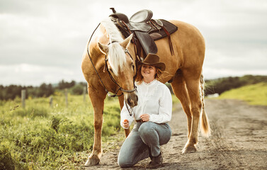 A woman, proudly wearing a cowboy hat, stands next to her horse