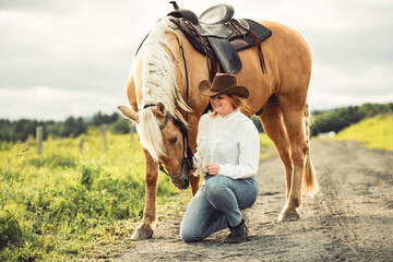 A woman, proudly wearing a cowboy hat, stands next to her horse