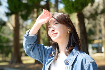 明るい日差しの中で手をかざして笑顔を見せる女性の春のポートレート