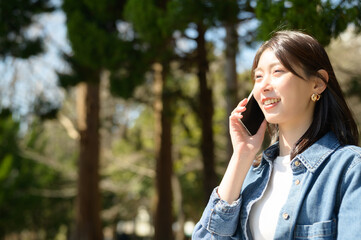 緑あふれる公園で通話しながら柔らかく笑う女性の自然な表情