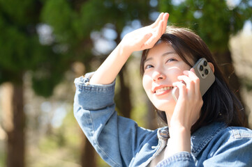 春の光を受けながら笑顔で電話する女性の開放的な一瞬