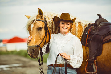 A woman, proudly wearing a cowboy hat, stands next to her horse