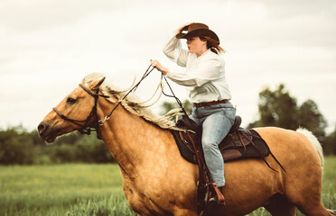 A woman is skillfully riding a horse gracefully in a lush field