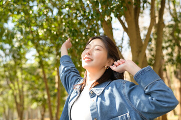 春の日差しを浴びながら両手を大きく伸ばして開放感を楽しむ女性