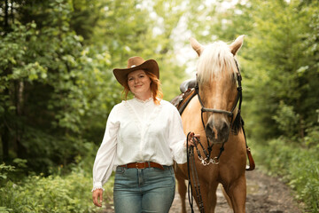 A woman is wearing a cowboy hat while riding a horse in an open field