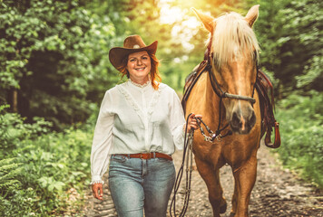 A woman is wearing a cowboy hat while riding a horse in an open field